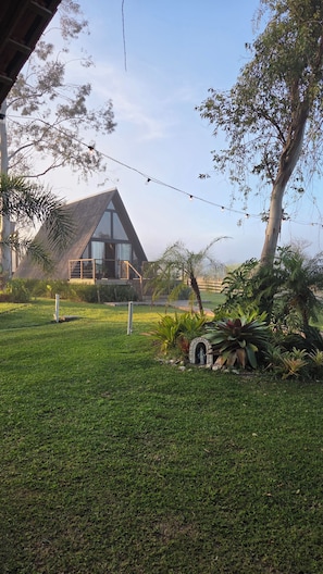 A modern house with a sloped roof, surrounded by a well-maintained lawn and various plants.