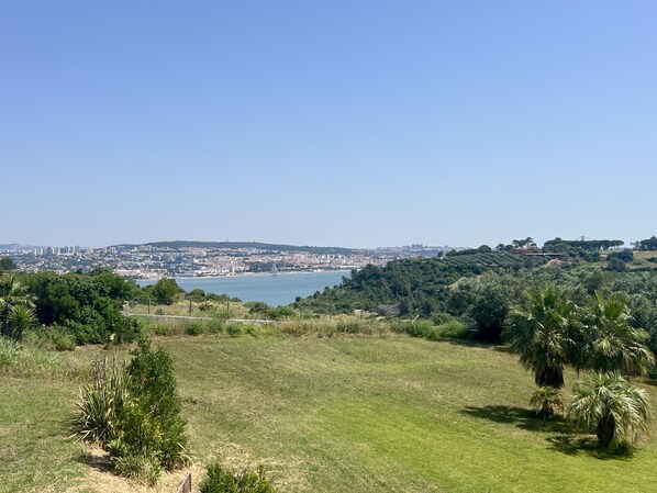 A coastal cityscape with a view of the sea and hills. - Villa Tagus Gardians (Trafaria)