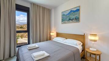 A hotel room with a large bed, two bedside lamps, a painting on the wall, and a window with curtains.