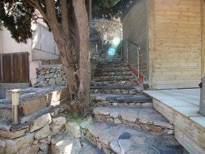 A stone staircase leading to a wooden door, surrounded by a stone wall and a tree. - House with sea view, pets allowed - 8 guests (Llançà)