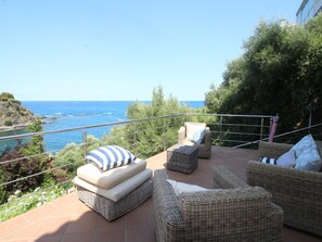 A terrace with wicker furniture, a view of the sea, and a railing. - House with sea view, pets allowed - 8 guests (Llançà)
