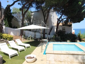 A pool area with lounge chairs, a white umbrella, and a view of the sea. - House with sea view, pets allowed - 8 guests (Llançà)