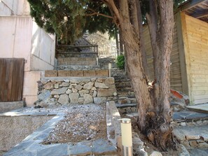 A stone staircase leading to a wooden door, surrounded by a stone wall and a tree. - House with sea view, pets allowed - 8 guests (Llançà)
