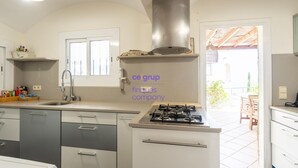 Una cocina con estufa a gas, pileta y ventana.