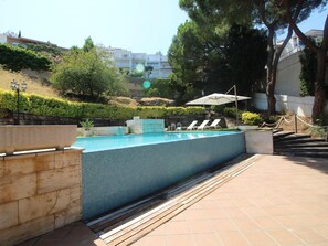 A swimming pool with tiled walls, surrounded by a wooden deck, and a few lounge chairs. - House with sea view, pets allowed - 8 guests (Llançà)