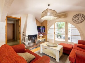 A cozy living room with a stone fireplace, red sofas, a white coffee table, and a large clock on the wall. - House with sea view, pets allowed - 8 guests (Llançà)