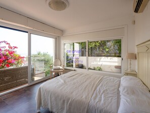 A bedroom with a large bed, a chair, a table, and a view through a sliding door to an outdoor area with plants. - House with sea view, pets allowed - 8 guests (Llançà)