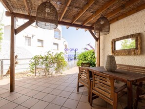 A covered patio area with wooden furniture, woven hanging lamps, and a view of a white building with a balcony. - House with sea view, pets allowed - 8 guests (Llançà)
