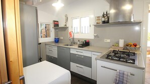 Una cocina compacta con estufa a gas, lavavajillas y refrigerador.