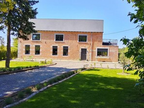 A two-story brick building with a flat roof, a front door, and a small balcony.