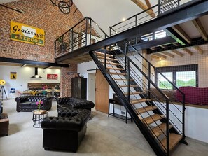 A loft-style room with exposed brick walls, a staircase, and a dining area.