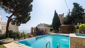 Une piscine avec vue sur la mer, entourée de bâtiments et de verdure.