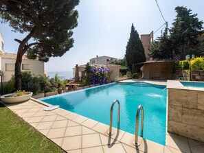 A swimming pool with a view of the sea, surrounded by buildings and greenery. - Splendid house, sea view - 6 guests (Llançà)