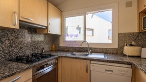 Une cuisine dotée de plans de travail en granit, d’une cuisinière, d’un lave-vaisselle et d’une fenêtre offrant une vue sur les bâtiments.