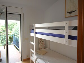 Een kamer met een stapelbed, een tafeltje en een raam met zonwering.
