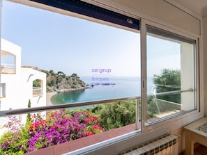 Ein Balkon mit Blick auf das Meer, ein weißes Gebäude und bunte Blumen.