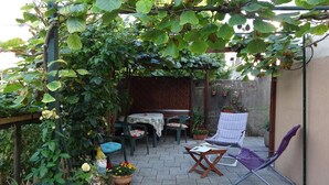 Une terrasse de jardin agrémentée d’une pergola, de mobilier d’extérieur, de plantes en pot et d’une statue.