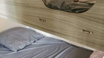 A bedroom with a bed, a nightstand, and a dresser with a mirror.