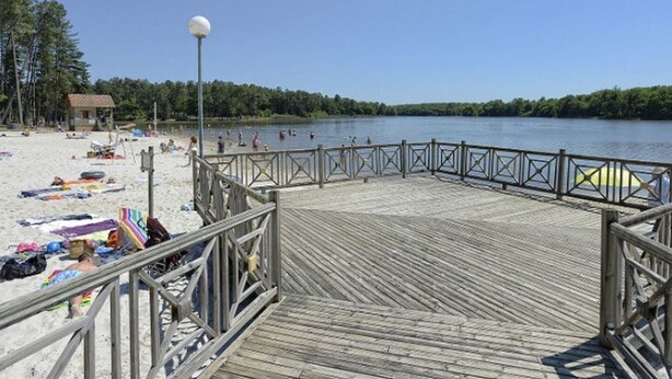 A wooden pier leading to a sandy beach with a clear view of the lake, surrounded by trees. - Mobile home, pets OK, AC - 6 guests (Verteillac)