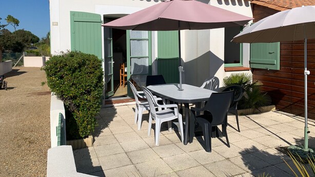A patio with a table and chairs, a green door, and a tiled roof. - House near beach, pets welcome - 4 guests (Saint-Hilaire-de-Riez)