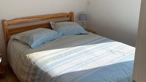 A single bed with a wooden headboard, two pillows, a bedside lamp, and a framed picture on the wall. - House near beach, pets welcome - 4 guests (Saint-Hilaire-de-Riez)