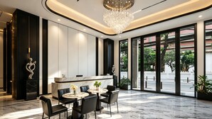 En moderne hotellobby med en marmorgulv, en receptionsdisk og en lysekrone.