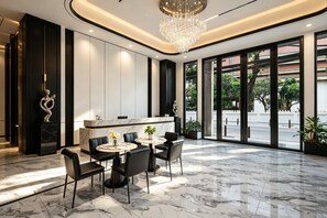 Un moderno vestíbulo de hotel con piso de mármol, una recepción y una araña.