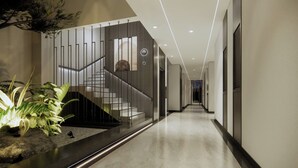 Een modern interieur met een trap, een plant en een gang naar een deur.