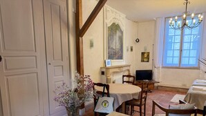 A dining area with a round table, chairs, a vase with flowers, a television, and a window with curtains. - Central studio, pets welcome - 2 guests (Blois)