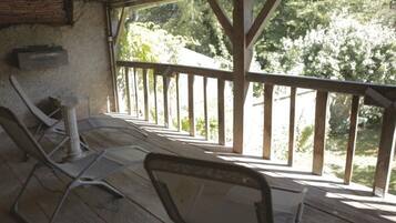 Un espace extérieur abrité, doté d’un plancher en bois et d’une rambarde, comprenant deux fauteuils et une petite table.