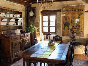 A rustic dining area with a wooden table, chairs, and a vintage clock. - Cozy lodging in city center - 8 guests (Saint-Amand-Montrond)