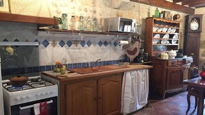 Une cuisine équipée d’une cuisinière à gaz, d’un four, de meubles en bois, d’un pare-feu en carreaux et d’une horloge murale.