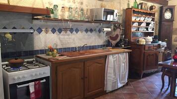 Une cuisine équipée d’une cuisinière à gaz, d’un four, de meubles en bois, d’un pare-feu en carreaux et d’une horloge murale.