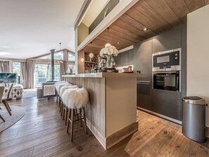 Eine moderne Küche mit Holzboden, Edelstahlgeräten und einer Bar mit Hockern.