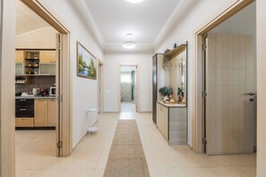 Ein Flur mit Küche links, einem Badezimmer mit Dusche und Toilette sowie einer Tür rechts.