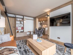 Ein modernes Wohnzimmer mit einer Couch, einem Couchtisch, einem Kamin und einer Küche im Hintergrund.