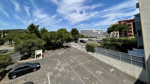Un parcheggio con posti delimitati, un edificio sullo sfondo e alberi.