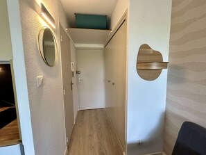 Ein Flur mit Holzboden, einem Spiegel, einer Tür und einer an der Wand befestigten Holzplatte.