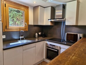 Eine kleine Küche mit Fenster, Edelstahlgeräten und einer Holz Arbeitsplatte.