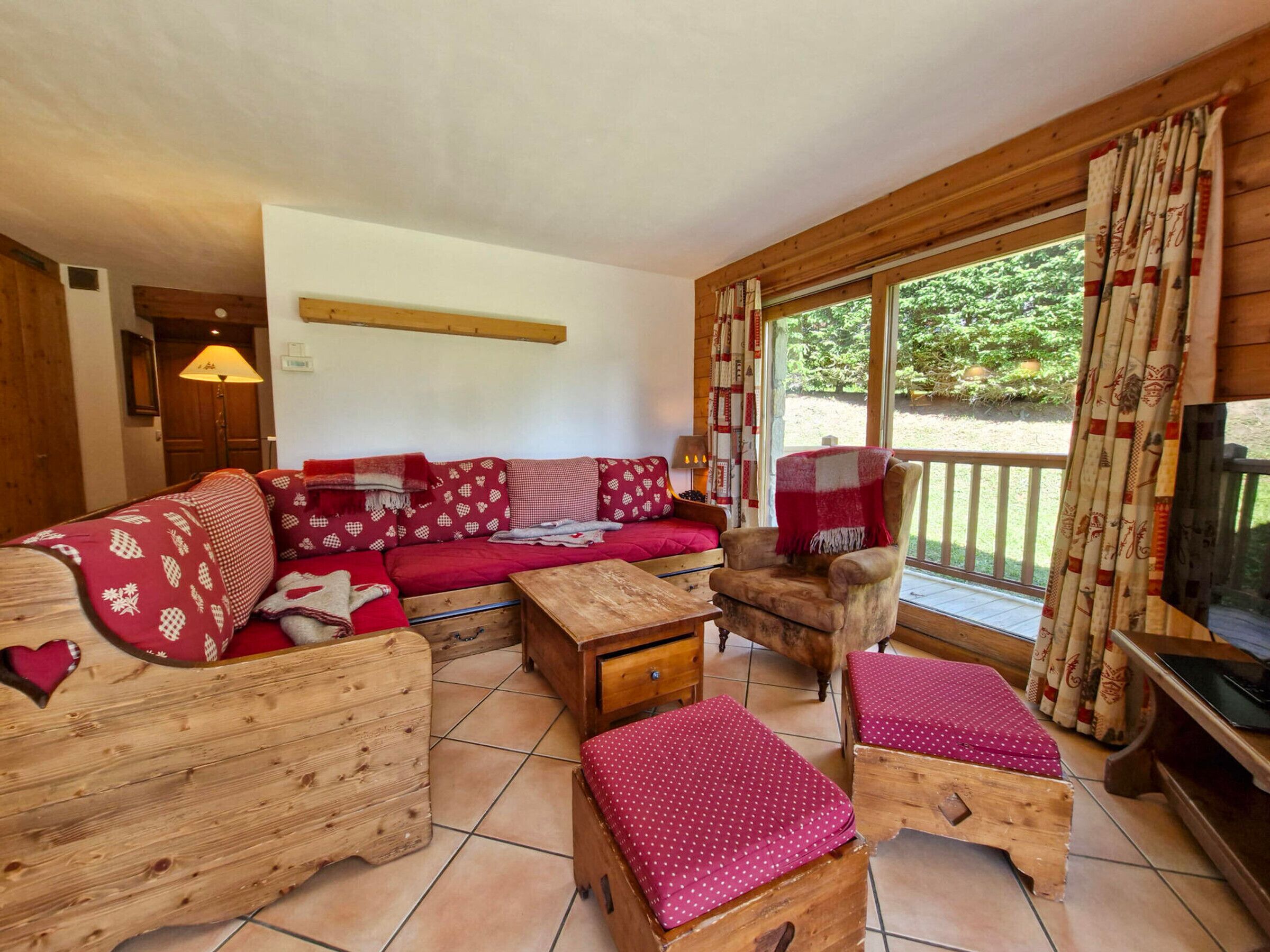 Ein gemütliches Wohnzimmer mit einem Holzsofa, einem Holzstuhl, einem kleinen Holztisch und einem Fernseher.