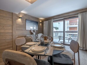 Un comedor con una mesa lista para cuatro, una cabeza de venado montada en la pared, y vistas de un paisaje nevado a través de grandes ventanales.