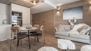 Ein moderner Wohnraum mit Essbereich, einer Couch mit flauschigem Überwurf und einer an der Wand befestigten Dekoration von einem Hirschkopf.