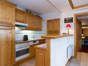 A kitchen with wooden cabinets, a stove, a sink, and a red lamp. - Cozy apartment in the center - 4 guests (Courchevel)