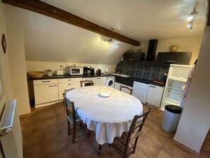 A compact kitchen with a dining table, white cabinets, a microwave, and a washing machine. - Apartment with parking, panoramic view - 12 guests (Vielle-Aure)