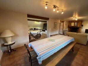A room with a bed, a table, a lamp, a sofa, and a kitchen in the background. - Apartment with parking, panoramic view - 12 guests (Vielle-Aure)