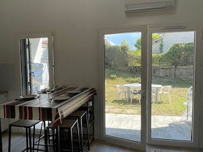 A kitchen with a long counter, stools, and a view of a garden through glass doors. - House with parking and garden - 4 guests (Capbreton)
