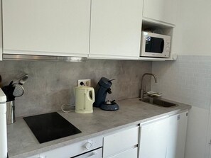 A kitchen with a microwave, kettle, kettle stand, and a black cutting board on the countertop. - House with parking and garden - 4 guests (Capbreton)