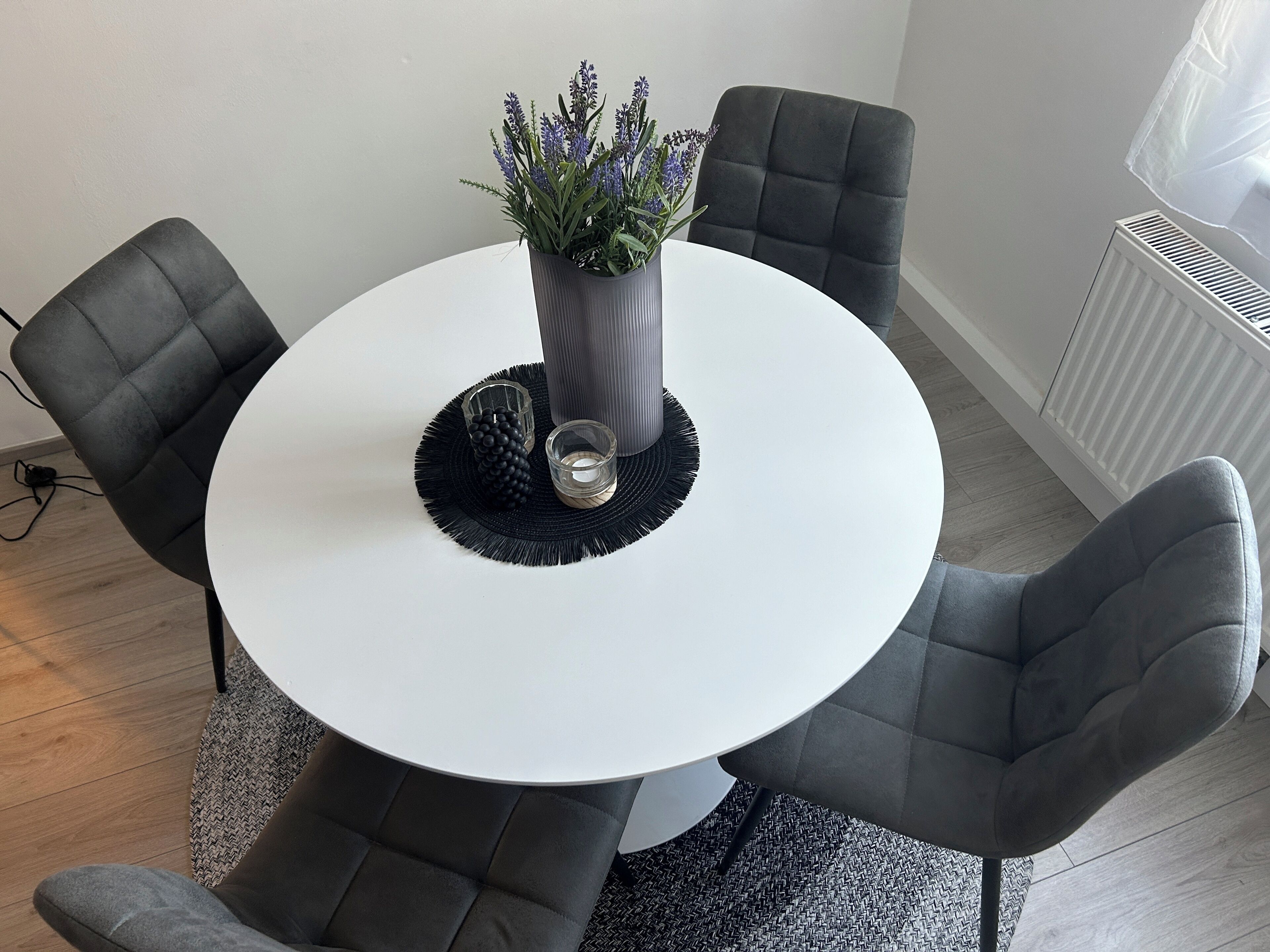 A round white table with a potted plant, two glasses, and a black decorative item.