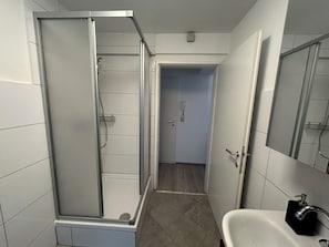 A bathroom with a glass-enclosed shower, a sink with a black soap dispenser, and a door leading to another room. - FarawayHomes Studios Schwertberg (Schwertberg)