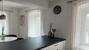Une cuisine moderne avec un plan de travail noir, des armoires blanches, une horloge et des objets décoratifs sur le rebord de la fenêtre.